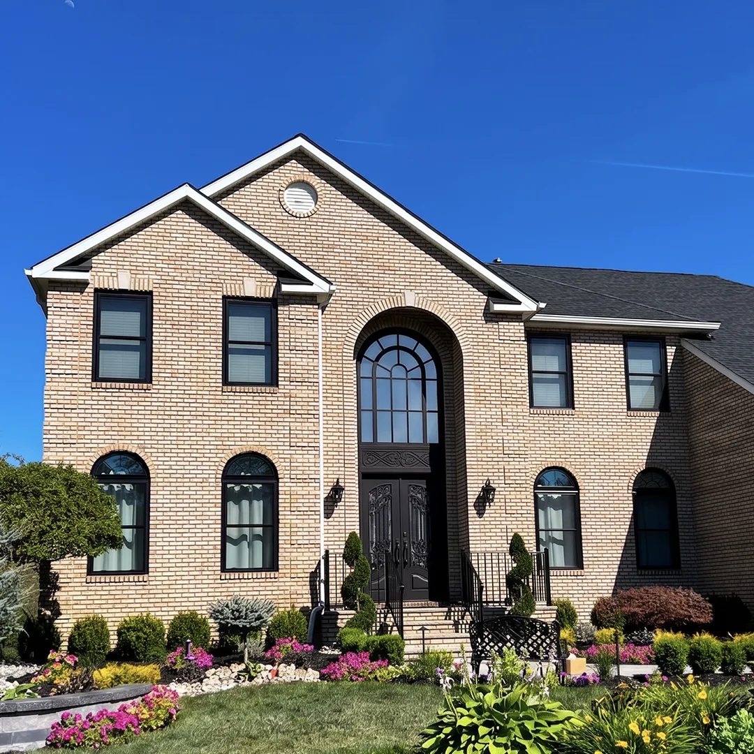 Brick home after black replacement windows were installed