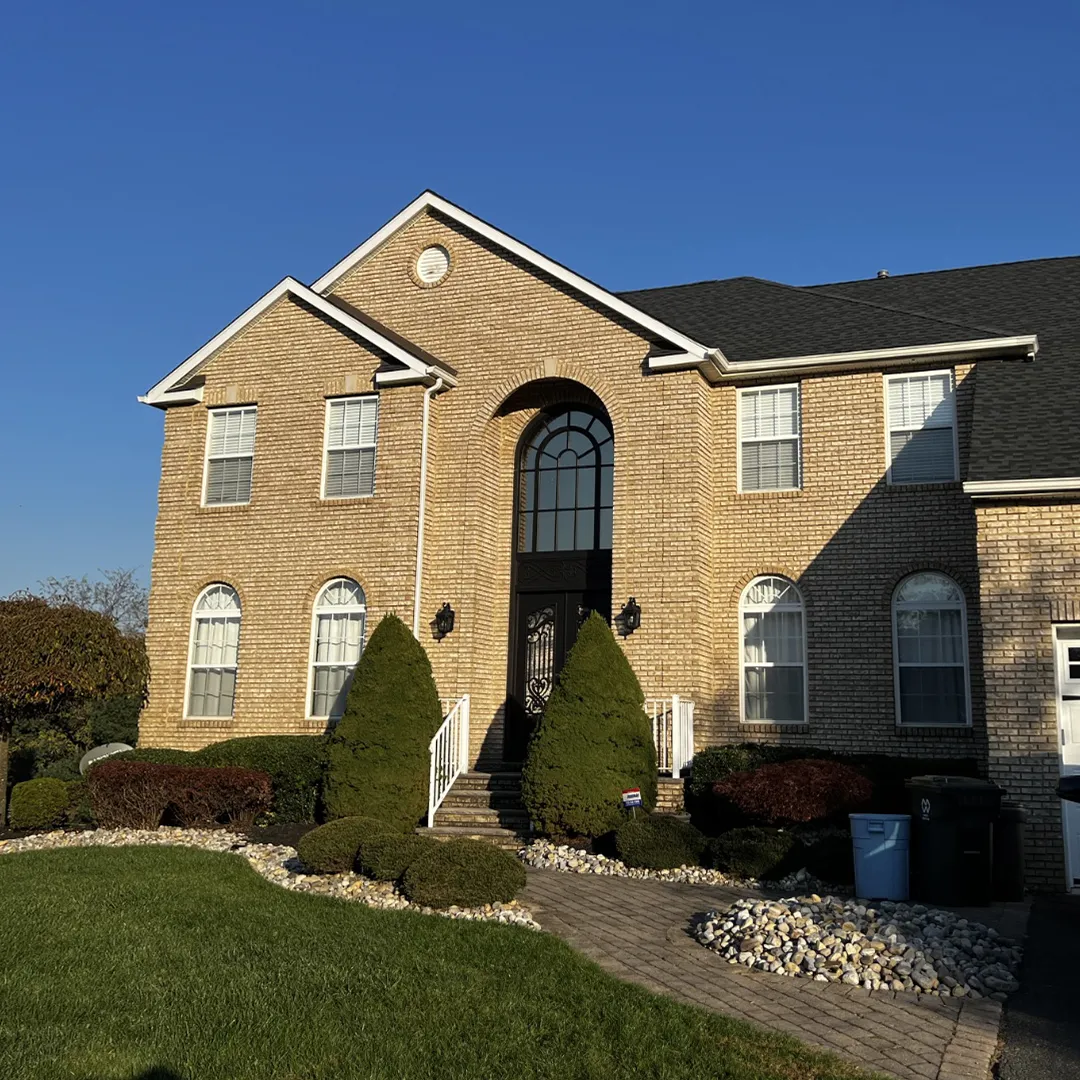Brick home before black replacement windows were installed