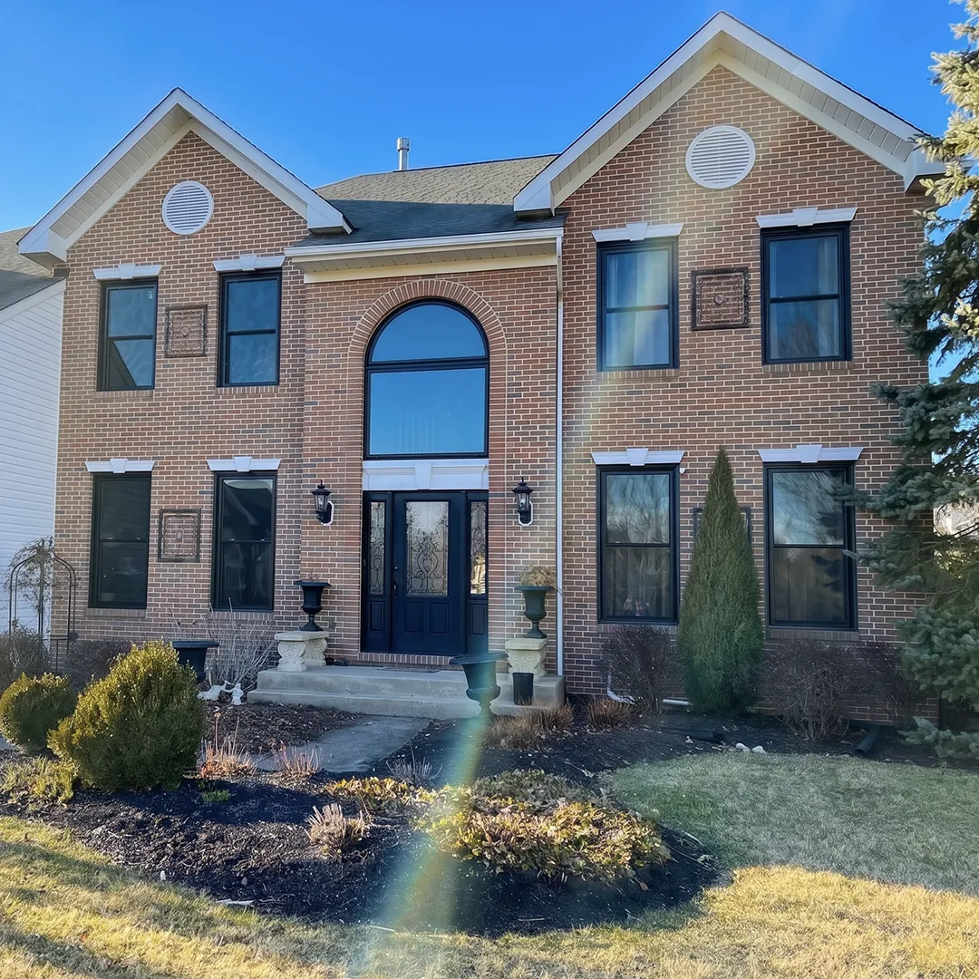 Two-story brick home after installing black replacement windows