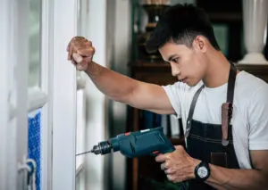 A window specialist drilling a hole to the window to fix the issue