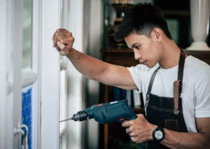 A window specialist drilling a hole to the window to fix the issue