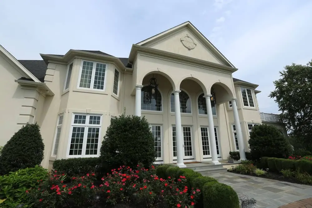 Large two-story home with multiple windows and a landscaped entrance