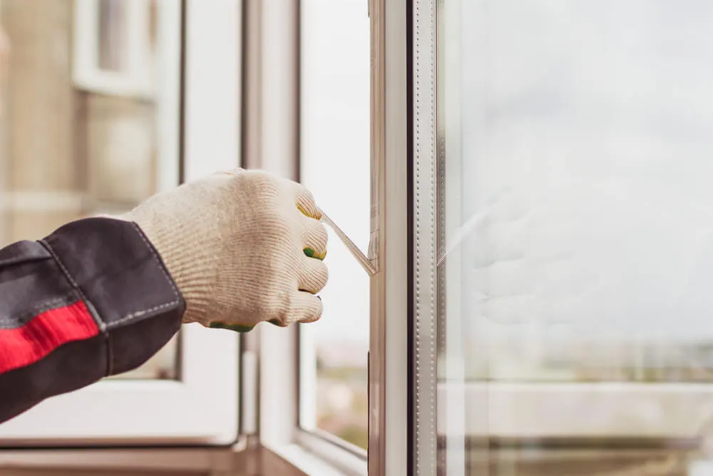 Person putting plastic film on windows.