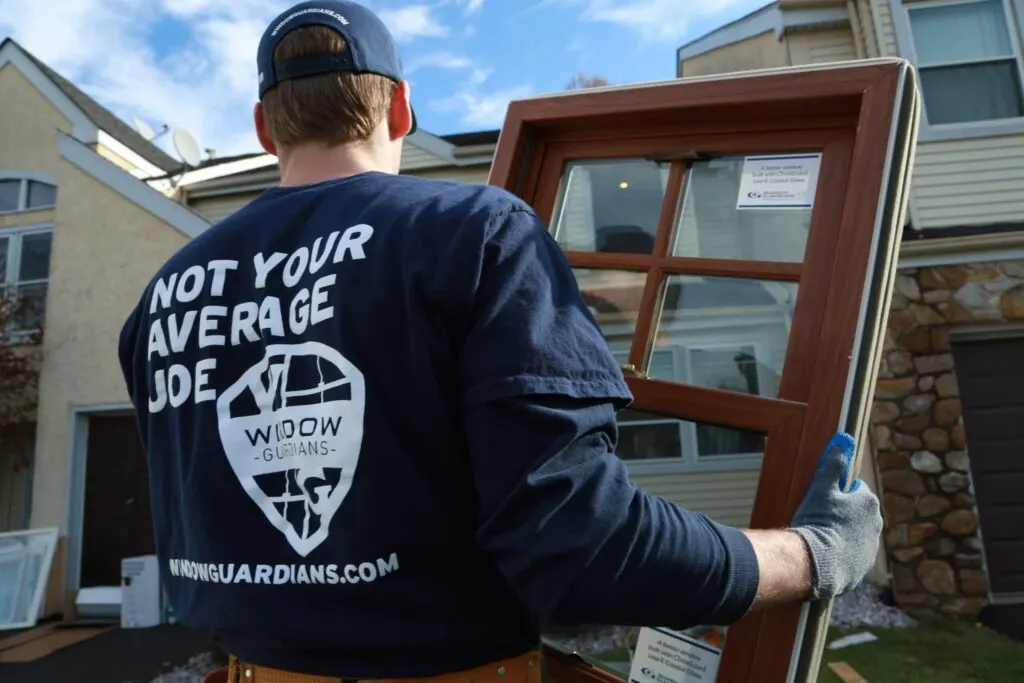 A professional from Window Guardians carrying a new window to a client’s home