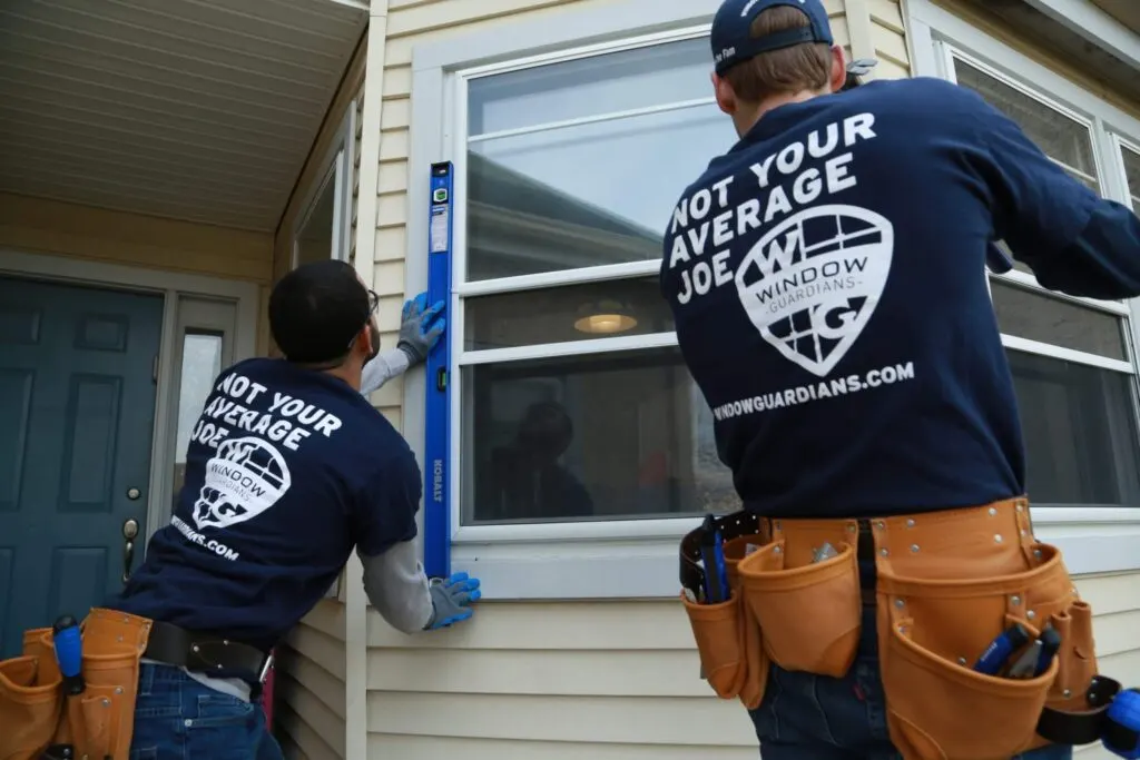 Two Window Guardians installers fitting a replacement window at a home