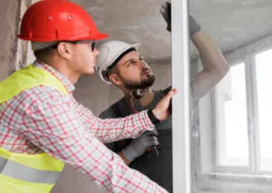 Two workers working hand in hand to fix the and install the window replacement in the room