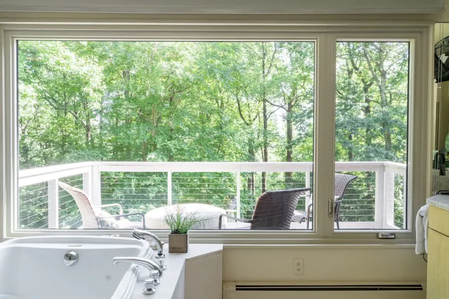 Bathroom picture window with a casement overlooking a wooded deck