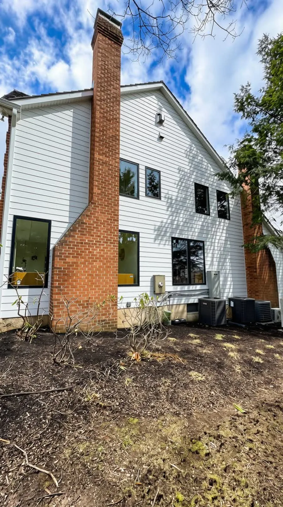 Rear of a home with new black-framed windows in fresh white siding