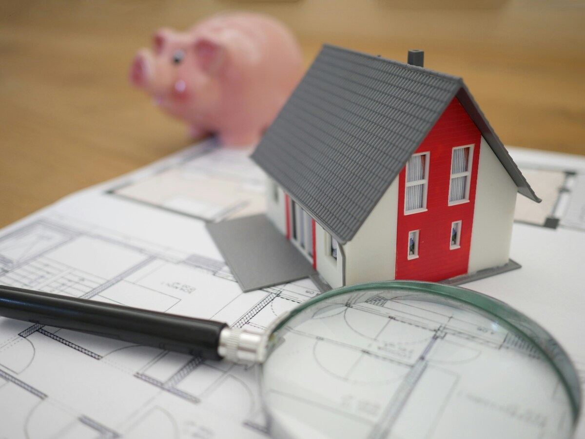 A miniature model house with floor plan and magnifying glass