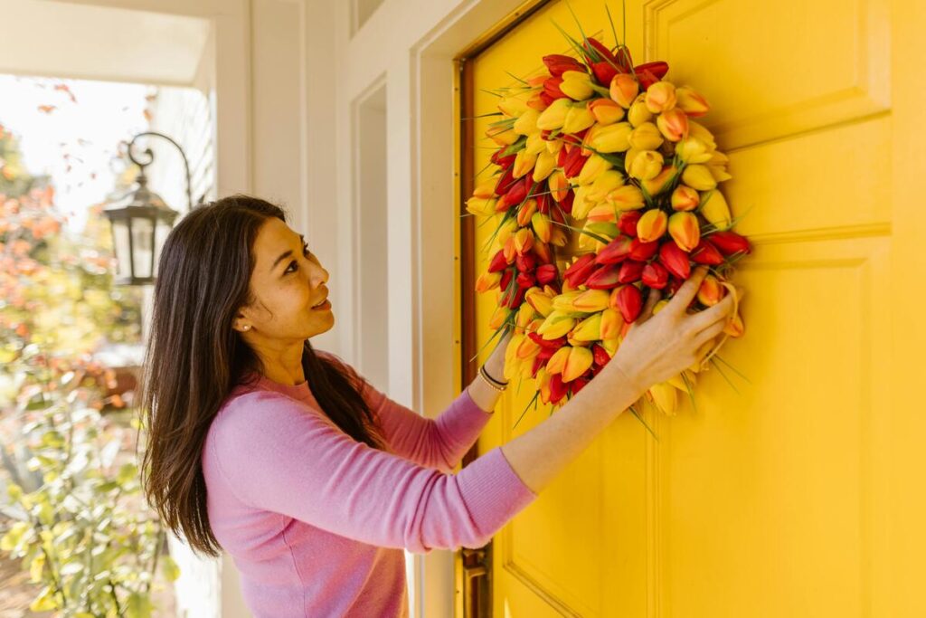 A woman hanging flowers on the front door